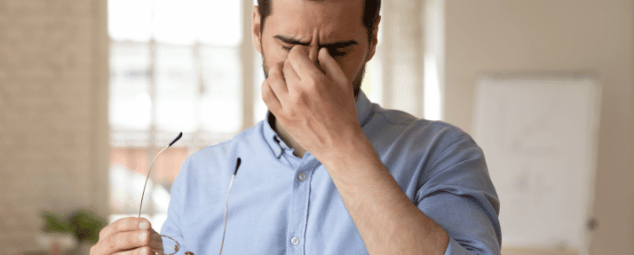 man with dry eyes holding his nose