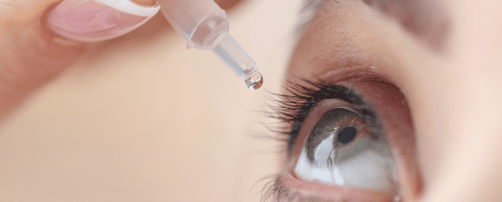 a person putting eye drops in eye