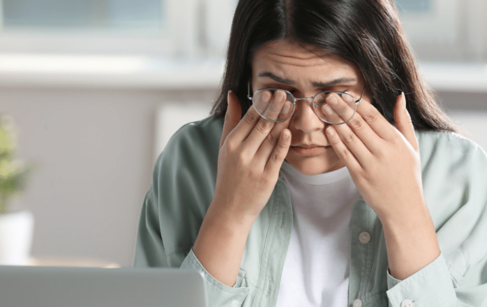 girl rubbing eyes at computer