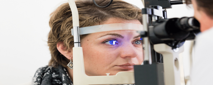 optometrist examining patient eyes with slit lamp